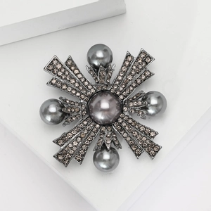Détail d'une broche vintage en alliage noir avec perles grises et strass brillants