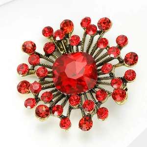 Close-up of vintage sunburst brooch with red square crystal and antique gold alloy