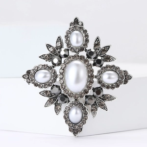 Macro detail of Baroque brooch with silver metal base, white pearls and black gemstones