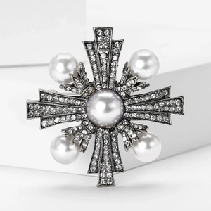 Détail macro d'une broche croix rétro en alliage avec perles blanches et strass