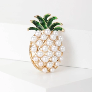 Detailed close-up of a pineapple brooch with white pearls and green enamel on a golden base