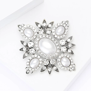 Macro view of vintage Baroque brooch with pearls and rhinestones on silver alloy