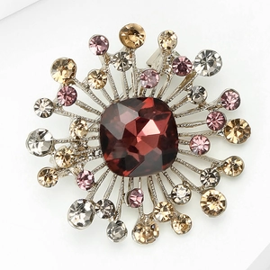 Macro shot of sunburst brooch featuring a deep red gemstone and multicolored rhinestones