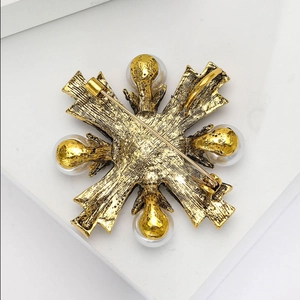 Vue détaillée du dos de la broche croix vintage dorée avec fermoir et perles