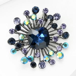 Detailed close-up of retro radial brooch with deep blue square gemstone and crystals