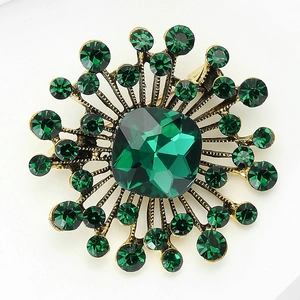Detailed close-up of emerald-cut green crystal brooch in vintage gold-tone setting
