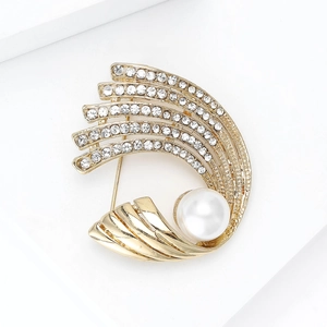 Detalle de elegante broche dorado con curva radiante, perla blanca y cristales finos