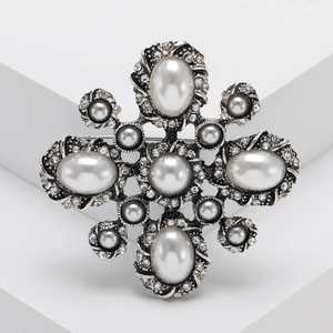 Vintage luxury brooch with central faux pearl and silver weave pattern crystal border