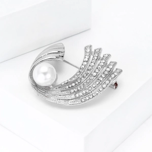 Detalle macro del elegante broche plateado con perla blanca y pavé de circonitas