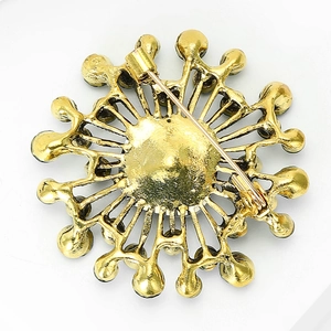 Macro detail of vintage gold starburst brooch back with secure safety pin clasp