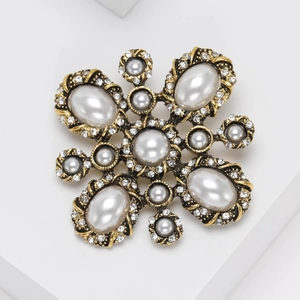 Vintage-style gold floral brooch with large pearls and sparkling crystals in a radial design