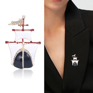 Broche voilier dorée avec émail bleu et strass présentée sur une veste de costume noire