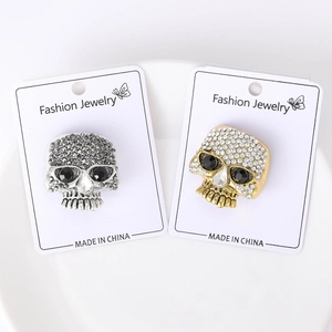 Detailed macro view of silver and gold punk skull brooches set with sparkling rhinestones