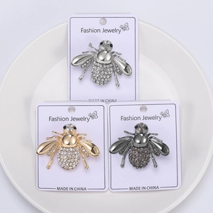 Vue détaillée de broches abeilles en or, argent et noir fusil avec strass étincelants
