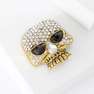 Macro shot of vintage gold skull brooch featuring sparkling rhinestones and black gem eyes