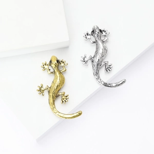 Gecko lizard brooches in gold and silver finish with black gemstone eyes on display