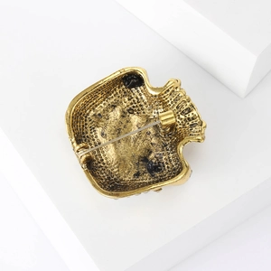 Detailed back view of a gold skull brooch showing a secure safety pin clasp and texture