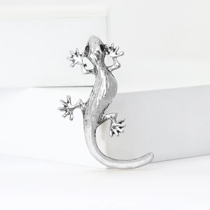 Vintage silver gecko brooch with black gem eyes on a white minimalist background