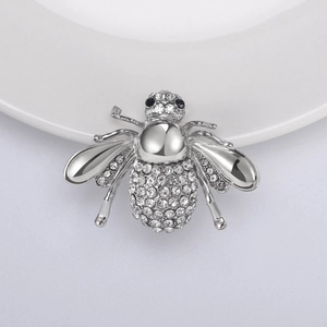 Vue macro d'une broche abeille argentée avec strass scintillants et détails d'ailes polis