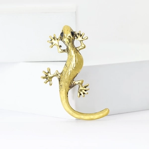 Golden gecko brooch in hammered alloy finish with black stone eyes on white blocks