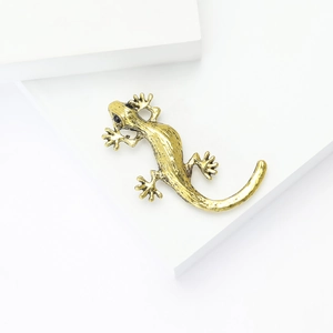 Detail view of vintage gold lizard brooch with textured skin and black stone eyes