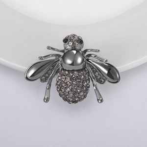 Détail d'une broche abeille avec strass gris taupe et ailes polies sur métal gris foncé
