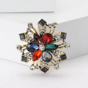 Macro shot of a vintage flower brooch featuring colorful teardrop crystals and gold metal