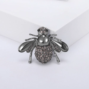 Broche abeille vintage en métal noir avec cristaux gris étincelants sur socle blanc