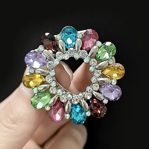 Détail macro d'une broche ronde sertie de cristaux colorés en forme de goutte et de strass fins