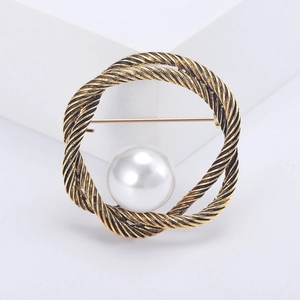 Détail de la broche ronde en corde dorée vintage avec une perle blanche centrale