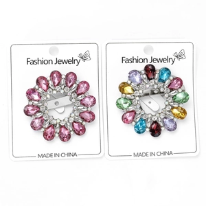Détail de broches en couronne florale serties de cristaux colorés sur des cartes blanches