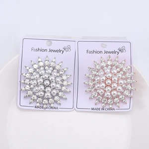 Close-up of silver and rose gold sunflower brooches with pearls and rhinestones