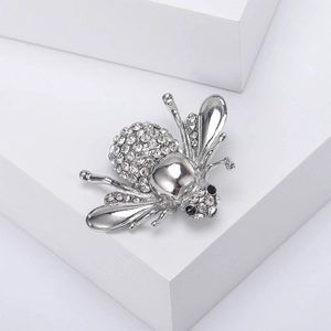 Vue macro d'une broche abeille argentée avec strass sur un support blanc pur