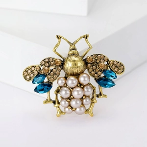 Detailed macro view of vintage bee brooch with pearls and blue crystal gemstones
