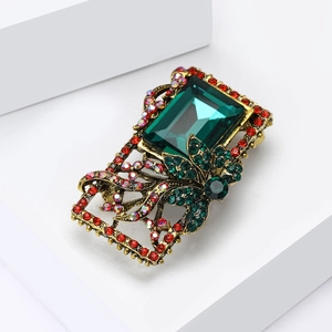 Macro shot of Baroque vintage brooch with emerald stone and intricate hollow metalwork