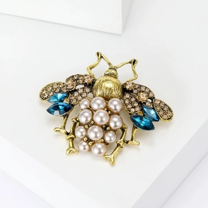 Vintage bee brooch with faux pearls, blue crystals, and champagne diamonds on white stand