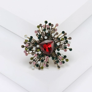 Detail of vintage flower brooch with red triangular stone and colorful rhinestones