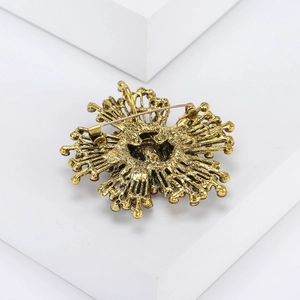 Macro view of vintage gold sunburst brooch showing back pin closure and matte texture