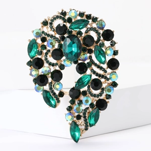 Macro view showing intricate green crystals and black gems set on a gold vintage brooch