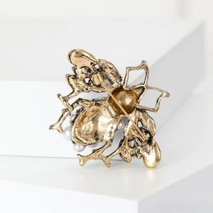 Macro detail of vintage gold bee brooch back showing safety pin clasp and pearls