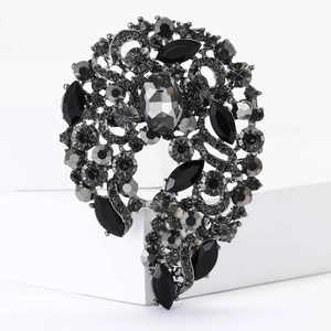 Macro shot of dark grey glass brooch with intricate alloy base on white background