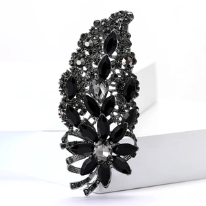 Detail view of a vintage gunmetal floral brooch with black rhinestones on a white stand