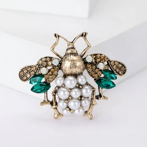Detail of vintage bee brooch with pearls and crystals on white geometric stand