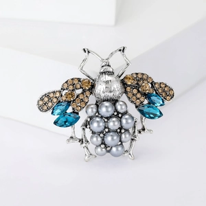 Close-up of vintage bee brooch with champagne crystals and grey pearls on silver alloy
