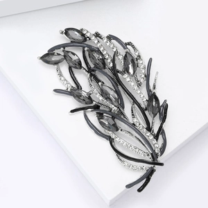 Détail macro d'une broche plume vintage avec strass gris et émail noir sur alliage
