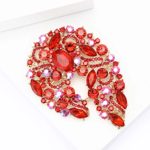 Elegant large gold alloy brooch with faceted red and AB crystals on a white pedestal