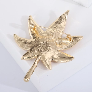 Back view of gold leaf brooch with rhinestones on a white geometric stone base