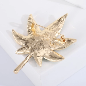 Rear view of gold maple leaf brooch showing safety pin clasp and rhinestone leaf stem