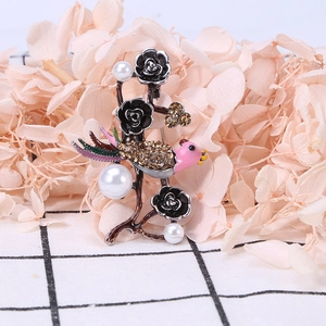 Vintage bird and rose brooch with rhinestones and pearls on a floral background