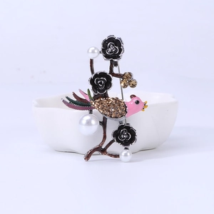 Detail of vintage silver bird brooch with pink enamel, black roses, and pearl accents
